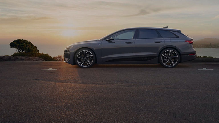 Audi electric car parked in on dusty road with sunsetting in the background