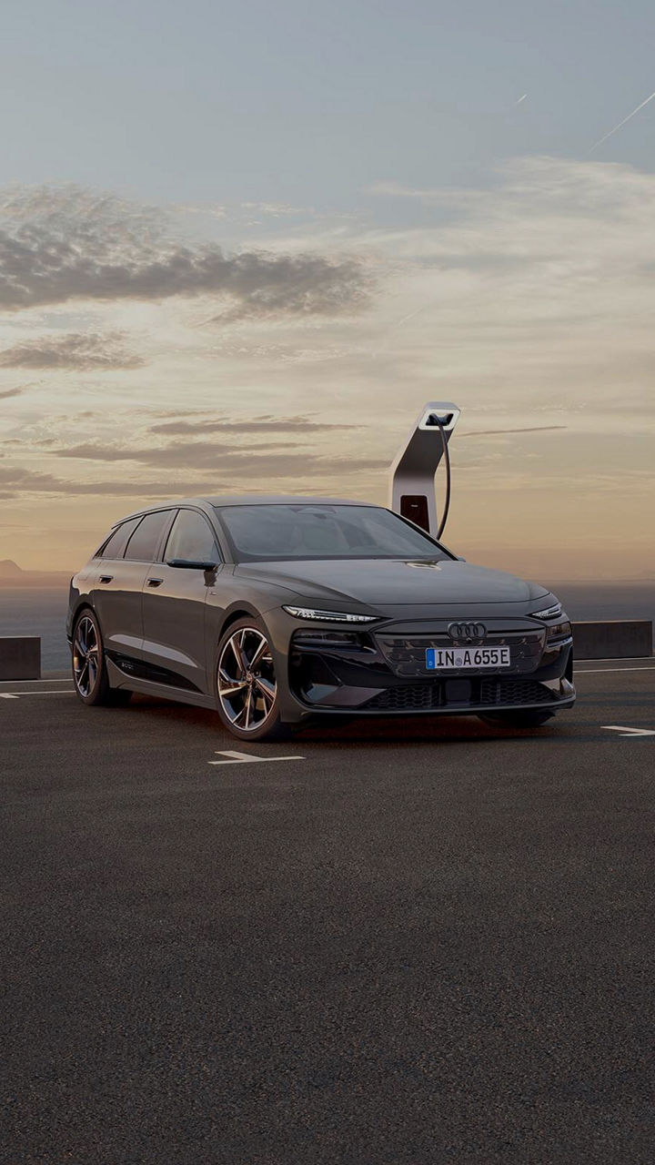 Audi electric car parked in on dusty road with sunsetting in the background