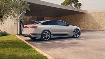 A6 Sportback e-tron parked outside a modern home under a covered area, with a minimalist stone wall in the background.