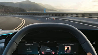 View from inside a car, showing a curved road ahead, speed of 50 km/h, with navigation and music player displayed on the dashboard.