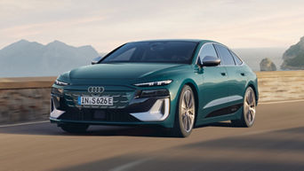 A sleek teal Audi S6 Sportback e-tron drives along a coastal road with mountains in the background.