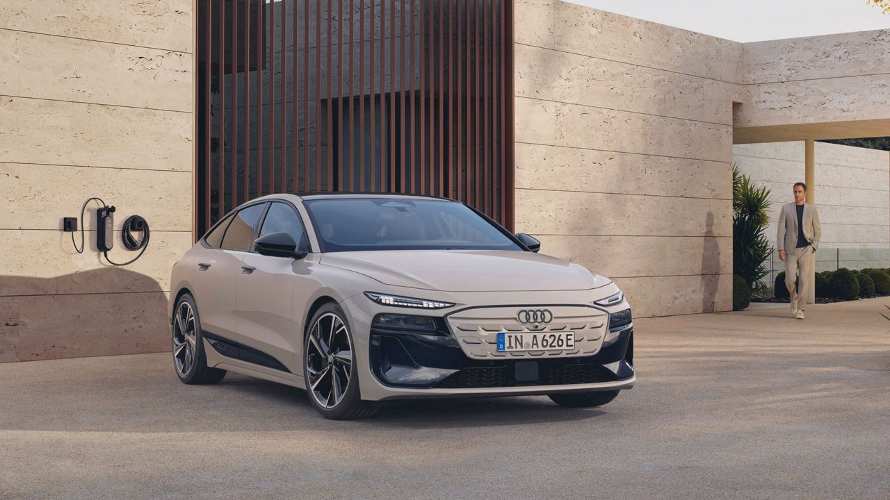 An Audi electric car parked near a charging station outside a modern building.