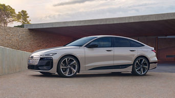 Audi sedan parked in a minimalist outdoor setting with stone walls and modern architecture in the background.