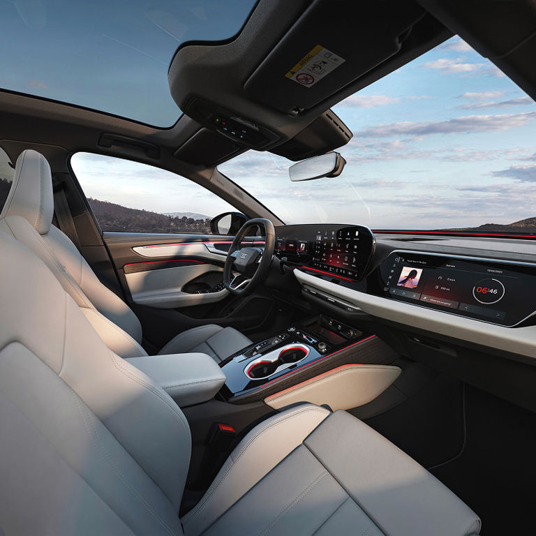 The interior of an Audi A6 Avant as seen from the passenger seat with focus on the driver dashboard and steering wheel