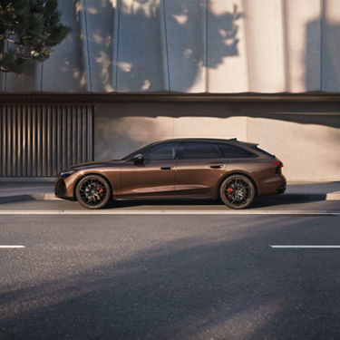 Brown Audi A6 Avant parked at the side of the road with building at the back