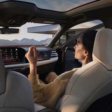 Interior of an Audi car with passenger sitting relaxed as viewed from the back seat behind the driver