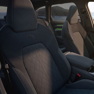 Interior shot of modern car seats featuring a sleek design, textured fabric, and illuminated accent near the console.