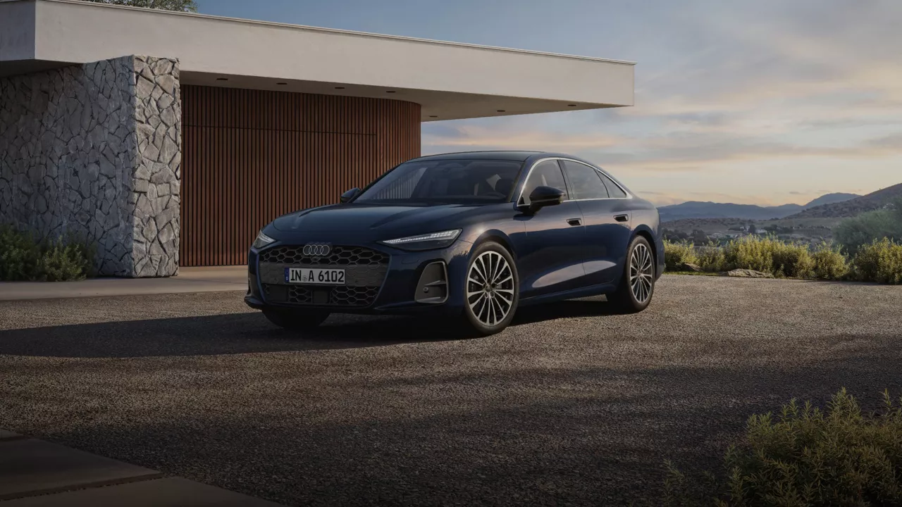 A sleek blue Audi sedan parked in front of a modern home, with mountains and a clear sky in the background.