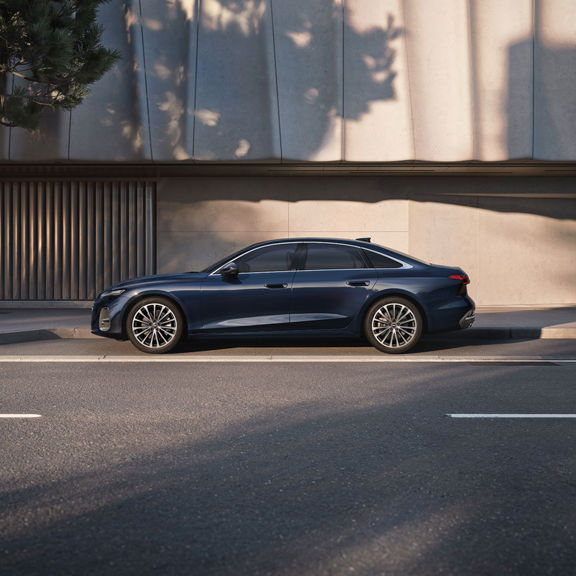 Blue Audi A6 Saloon parked on the side of the street in front of a concrete building