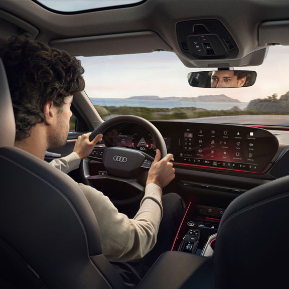 Interior view of an Audi from the back seat, while a man is driving