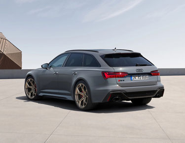 A grey Audi RS 6 Avant performance parked on a rooftop with a clear sky background.