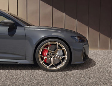 Close-up of a grey car's front wheel with red brake callipers.