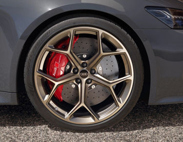 Close-up of an Audi's wheel with a red brake calliper and perforated disc brake.