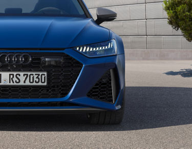 Close-up of a blue car's front grille and headlight.