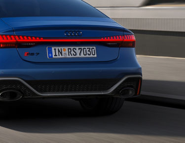 Rear view of a blue sedan with distinctive taillights in motion on a road.