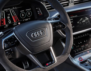 Interior view of an Audi vehicle focusing on steering wheel and digital dashboard displays.
