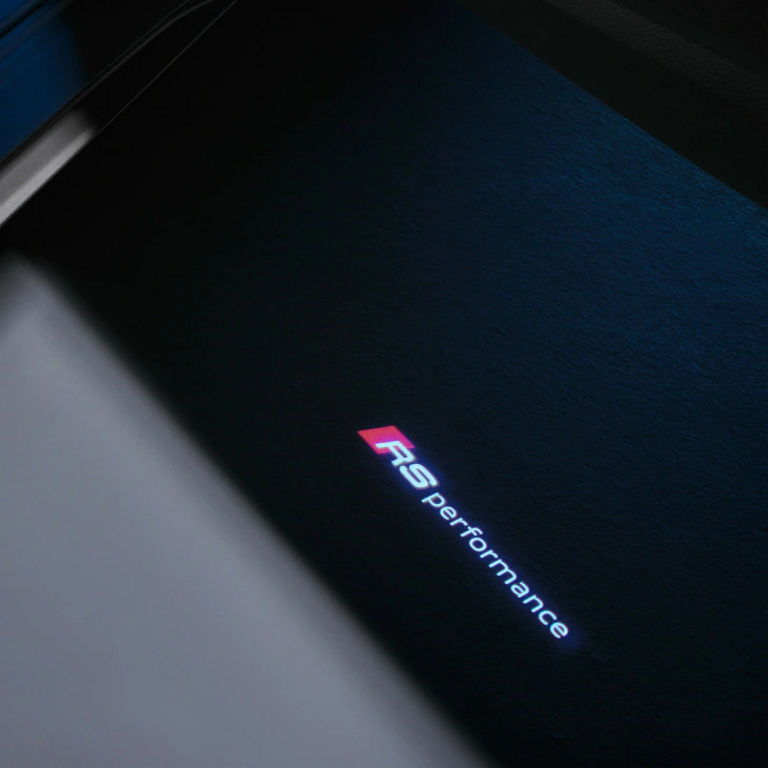 Close-up of a textured surface with the illuminated logo "RS performance" in red and white.