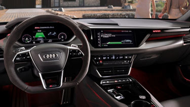 Interior of an Audi with digital displays, steering wheel, and red ambient lighting.