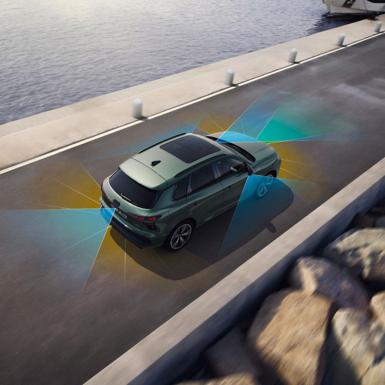 Aerial view of a green SUV on a roadway, showcasing advanced safety sensors with colourful detection zones around the vehicle.