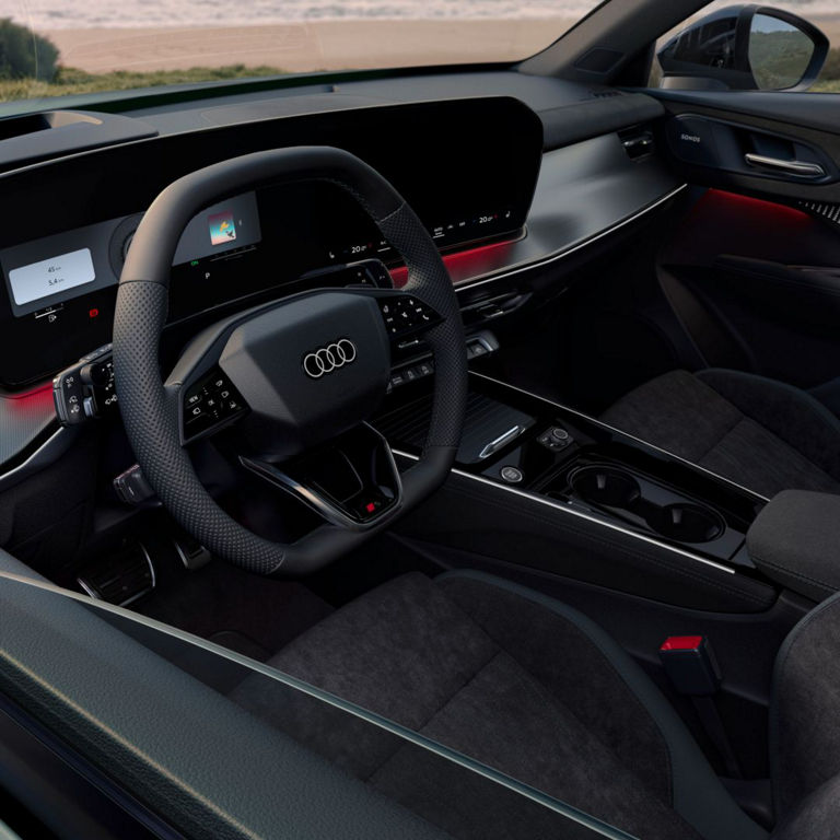 Interior view of a modern Audi car showcasing a sleek dashboard with dual screens, a stylish steering wheel, and ambient lighting.