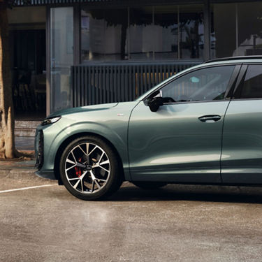 A sleek green SUV parked on a modern street, showcasing its stylish design and sport wheels against a contemporary building backdrop.