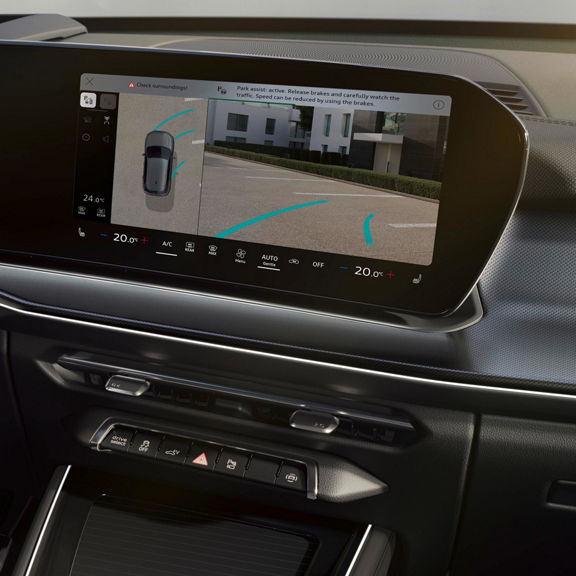 Audi Q3 digital display showing parking assist with camera view, trajectory lines, and climate controls below.