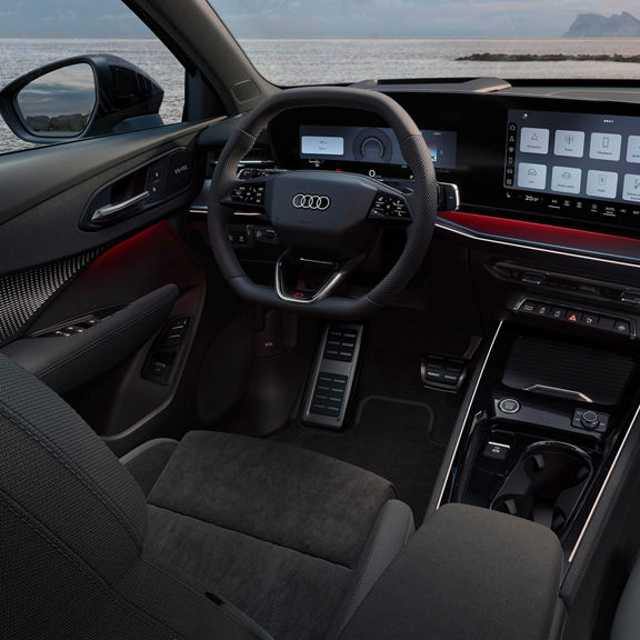 Audi Q3 interior with steering wheel, digital cockpit, infotainment touchscreen, ambient lighting, and sea view.