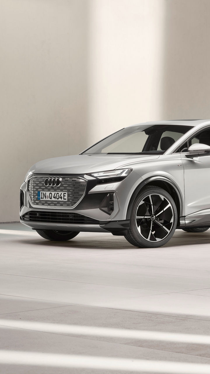 A silver Audi Q4 Sportback e-tron parked in a modern, minimalist setting with soft lighting and smooth surfaces.