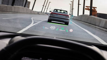 View from the driver's perspective in a Q4 Sportback e-tron showing a digital heads-up display with speed, distance, and road signs while driving.