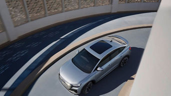 A silver Audi Q4 Sportback e-tron navigates a modern, curved ramp with intricate architectural details in the background.