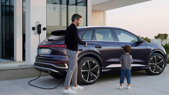 A man and a kid standing next to a Q4 e-tron charging