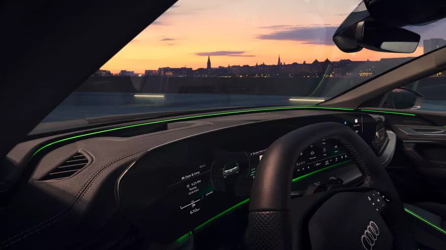 Interior shot of an Audi car, with subtle green ambient lights in display.