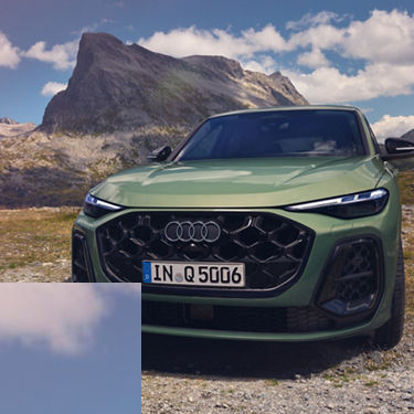 A green Audi SUV parked in a nature setting, with a tall mountain rock in the background.