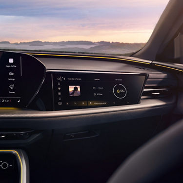 Close-up of a car multimedia screen, with a sunset view through the window.