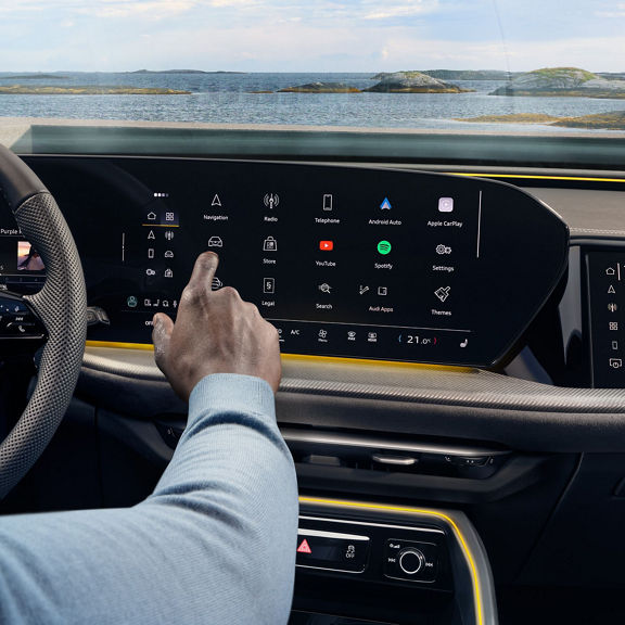 Interior view of a car showing steering wheel, dashboard, and multimedia interface.