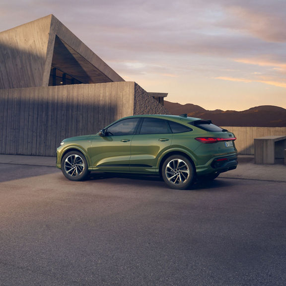 Green Audi SUV parked outside of a modern house.
