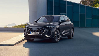 Black Audi SUV parked in a modern setting, showcasing its distinctive grille and stylish design against a minimalist backdrop.