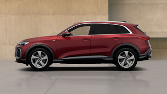 A red Audi Q5 SUV with modern design elements, showcasing its profile against a minimalist concrete backdrop.