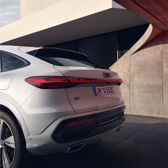 A white Audi Q5, showcasing its modern design, parked against a minimalist architectural backdrop with dramatic lighting.