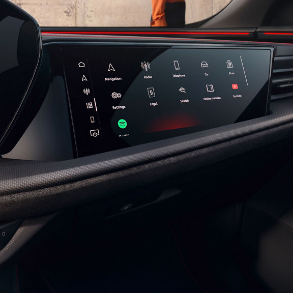 A modern car interior showing a sleek touchscreen display with icons for navigation, music, and settings, illuminated in ambient light.