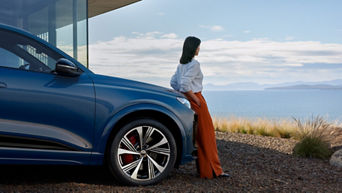 A woman leaning on the bonnet of an blue Audi SQ6 Sportback e-tron