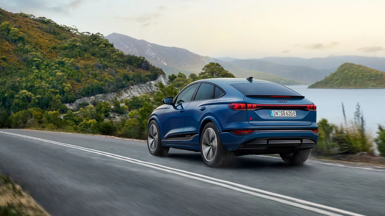 A blue Audi SQ6 Sportback e-tron driving on a lakeside road