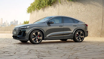 Grey electric SUV charging outdoors with city skyline in the background.