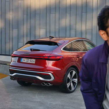 A red Audi SUV parked outdoors, in front of a texturised wall.