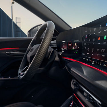 Interior shot, with steering wheel and infotainment screen visible.