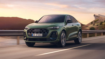 A green Audi Q5 Sportback driving along a scenic road at sunset, showcasing its sporty design and modern features.