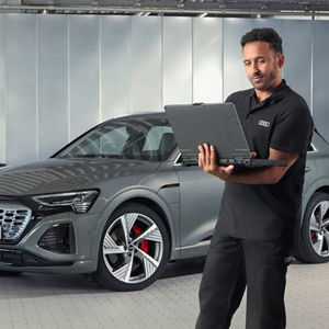 A mechanic wearing Audi overalls reading something from a computer