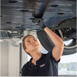 A mechanic sitting in a car while looking at a computer screen