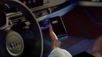 A female hand holding a phone with an Audi all launched