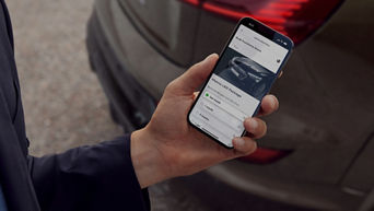 A hand holding a phone with an Audi app on screen